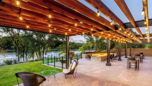 An outdoor patio area with wooden pergola, string lights, and seating arrangements. - Courtyard by Marriott Appleton Riverfront (Appleton)