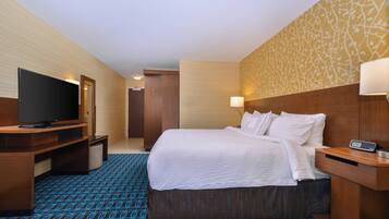 A hotel room with a bed, a television, a desk, and a lamp.