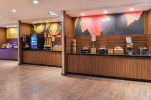 A reception area with a wooden counter, a coffee machine, and a refrigerator.