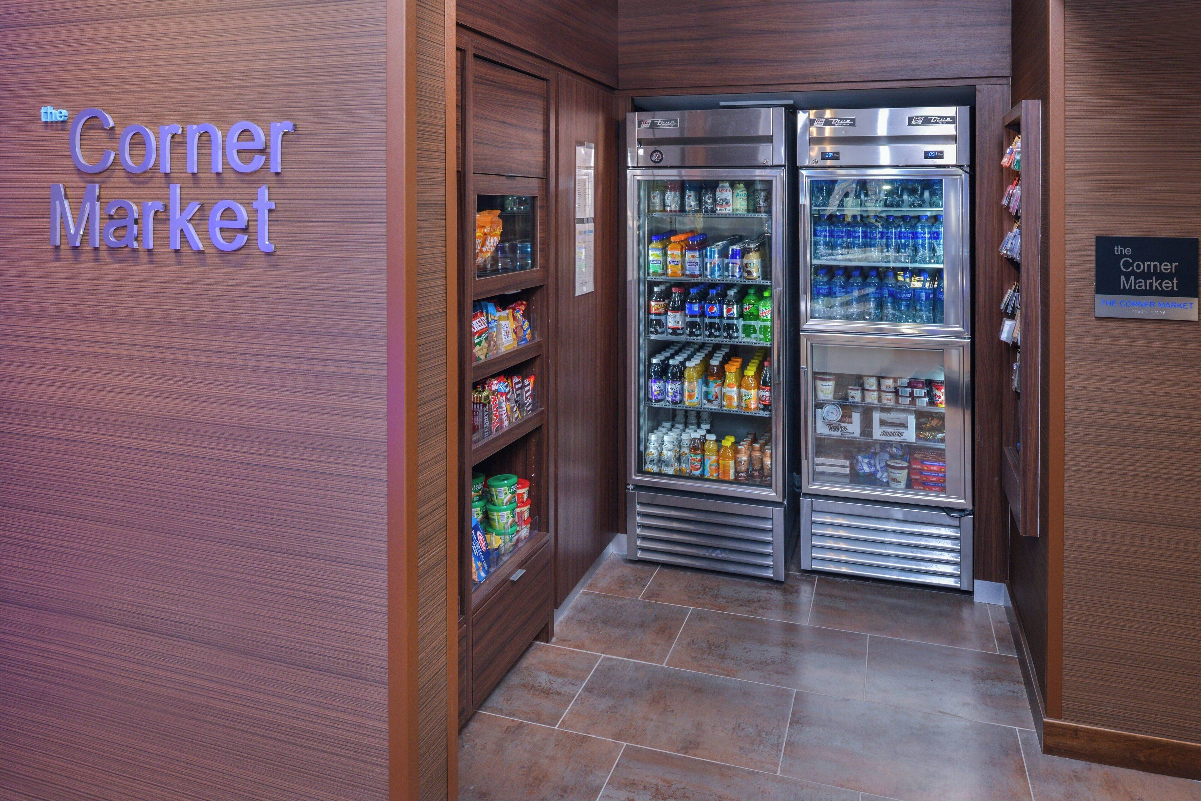 A corner market with refrigerated display cases and shelves stocked with various food items.