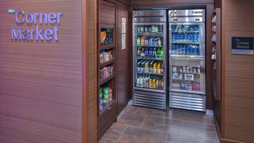 A corner market with refrigerated display cases and shelves stocked with various food items.
