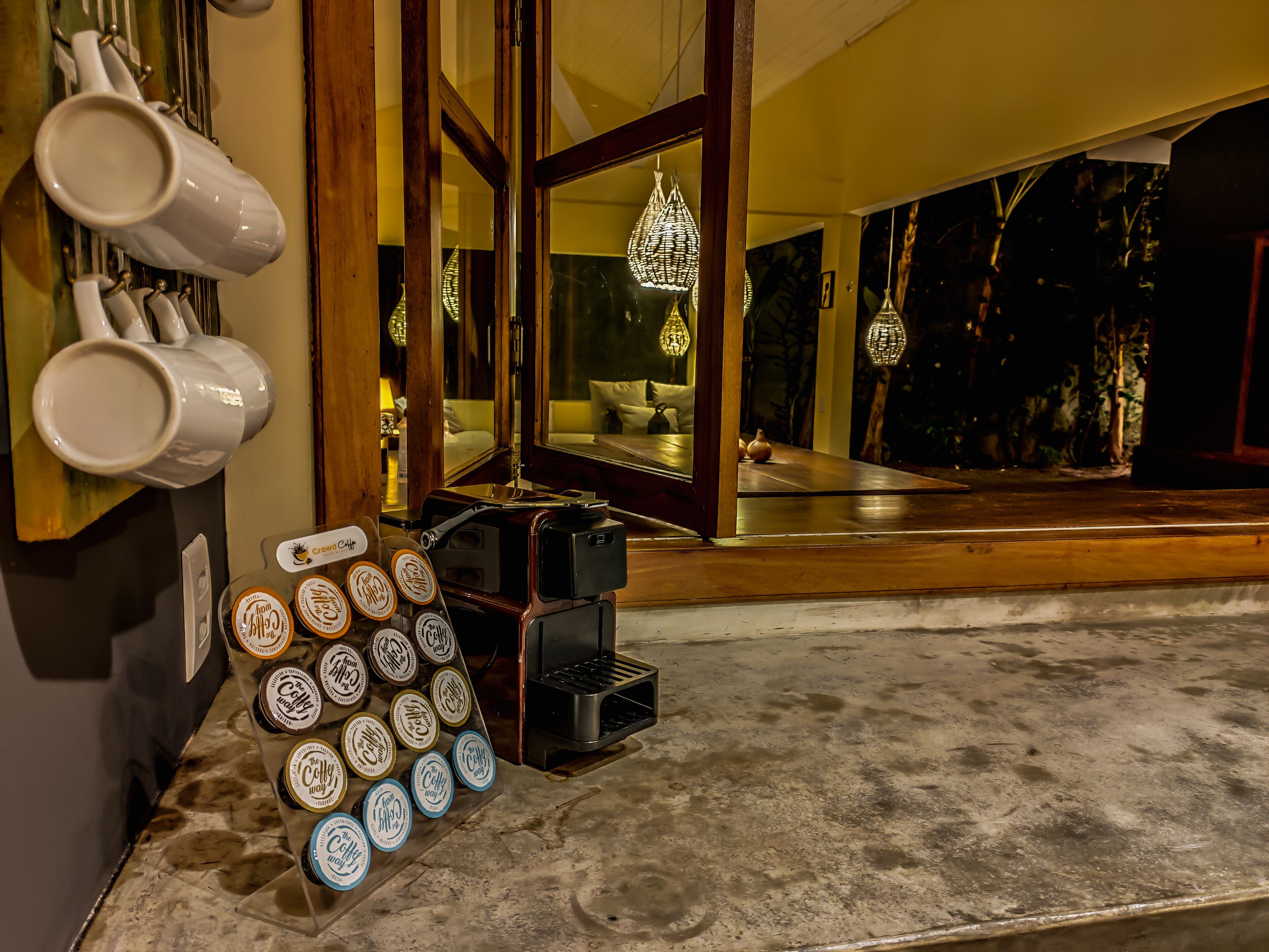 Una cafetería con una máquina de café, una exhibición de tazas de café y un espejo grande que refleja el salón.
