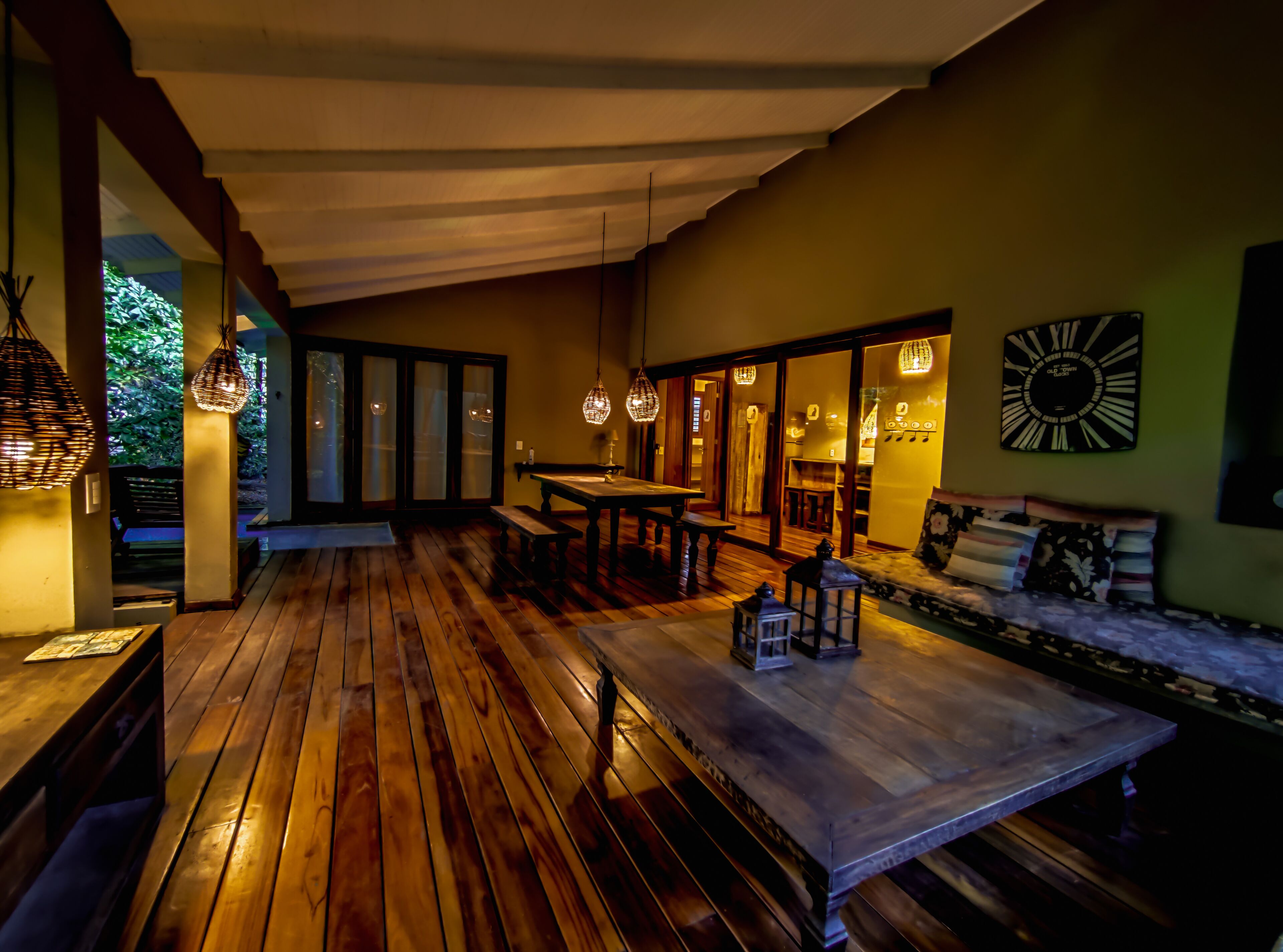 A wooden deck with a dining area, benches, and hanging lights.