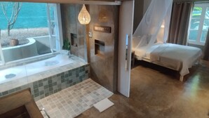 Une pièce spacieuse dotée d’une grande fenêtre, d’un lit, d’un petit coin salon et d’une pancarte indiquant qu’il s’agit d’une salle de massage.