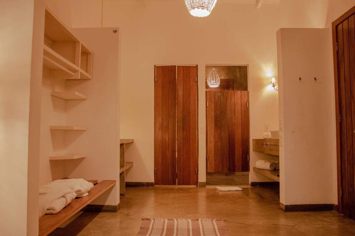 Un couloir avec des portes en bois, un banc avec des serviettes et un luminaire suspendu.