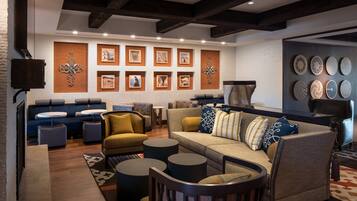A modern living room with a sofa, armchairs, and round tables. There are framed pictures on the wall and a fireplace.