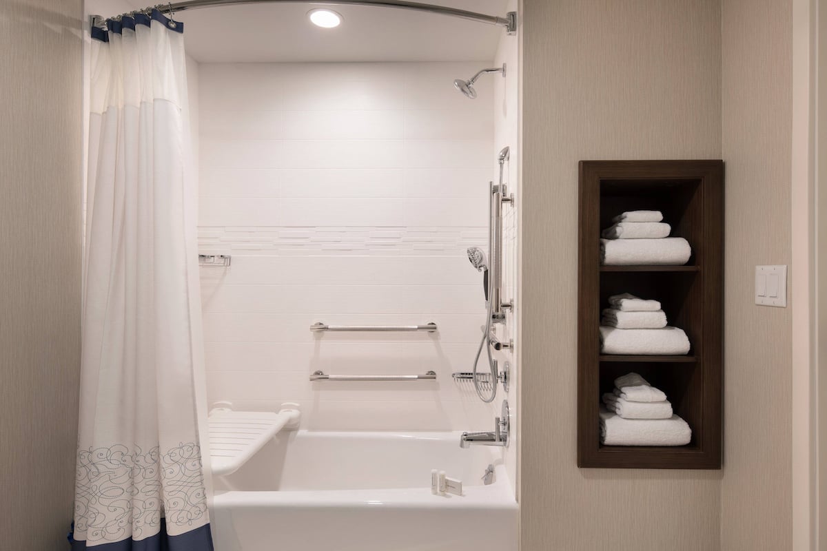 A modern bathroom with a bathtub, shower, and a towel rack.