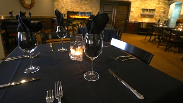 A dining table set with wine glasses, cutlery, and napkins. - Companion Hotel Motel (Hearst)