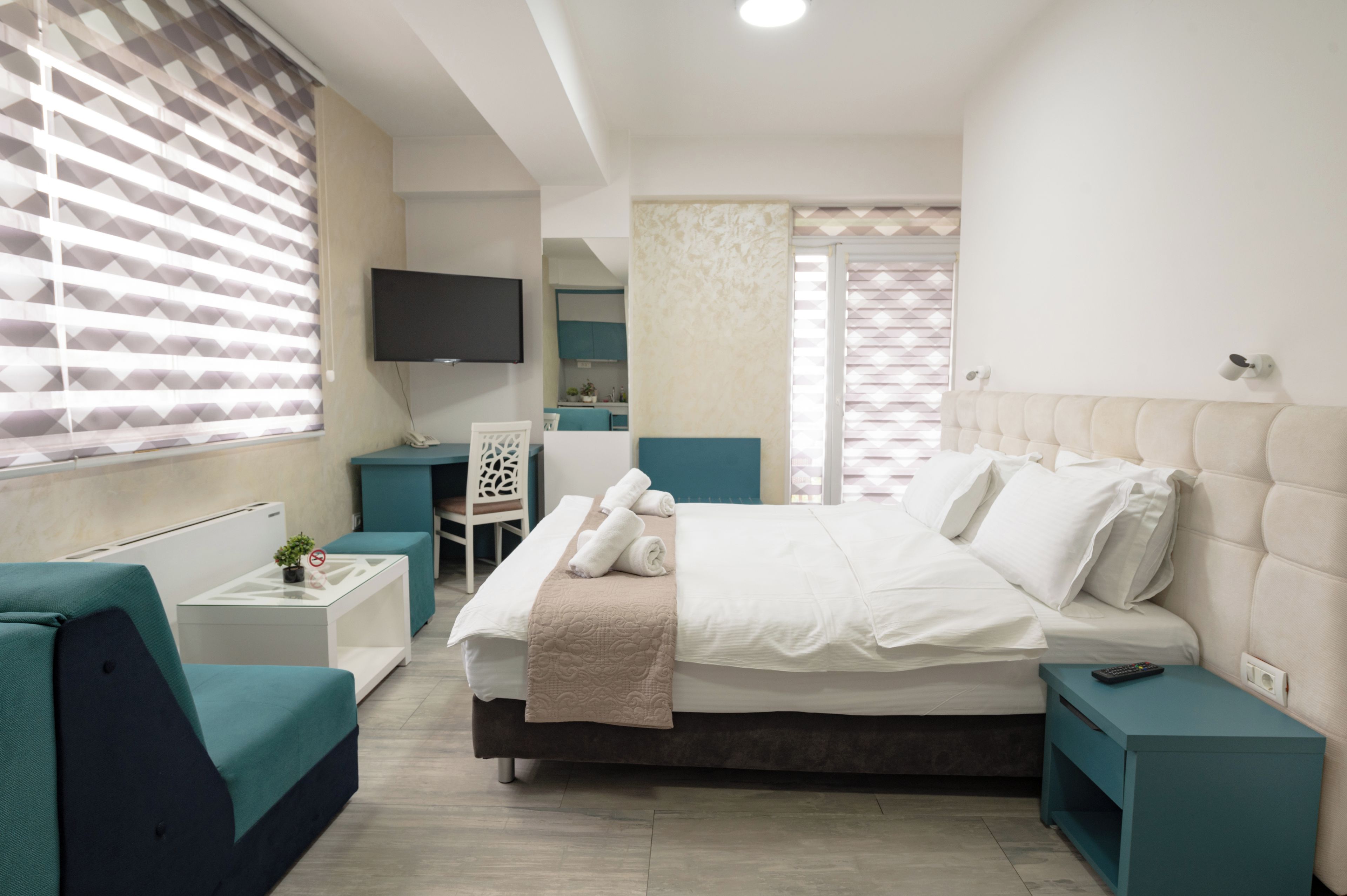 Une chambre moderne avec un grand lit, une télévision, un bureau et une chaise.