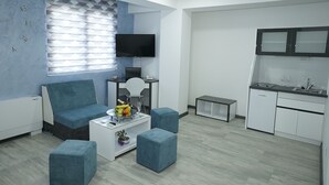 A modern living room with a sofa, ottomans, a coffee table, and a TV. There is a kitchen area with a sink and cabinets. - Astera Apart Hotel (Skopje)