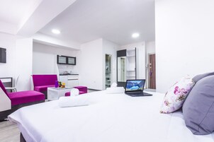 Habitación de hotel moderna con cama, escritorio, silla, televisor y baño.