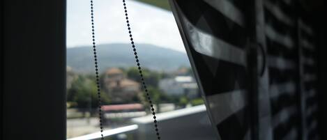 Vista a través de una ventana con cortina de cuentas, un vistazo al paisaje urbano y una montaña al fondo.