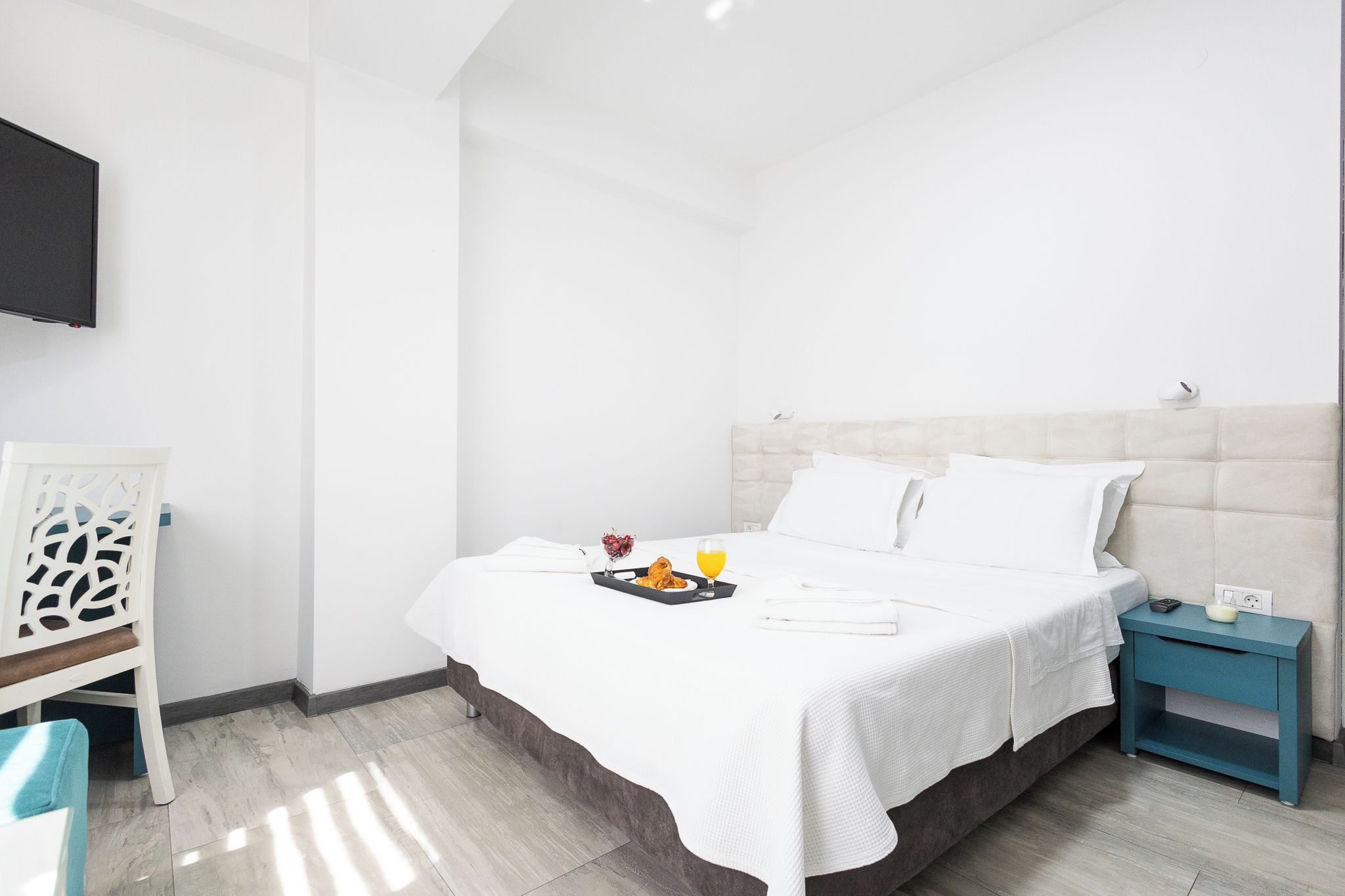 Ein Hotelzimmer mit Bett, Nachttisch und einem an der Wand befestigten Fernseher.