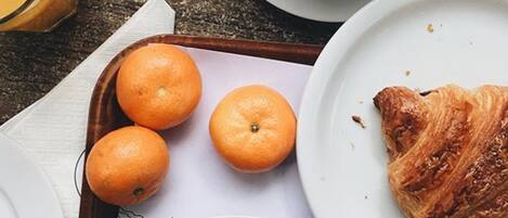 A tray with three oranges and a croissant on a table.