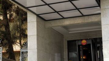 La entrada al Hotel Royal Marshall, con un cartel sobre la puerta, una escalera que lleva a la entrada y una pequeña mesa con una silla afuera.