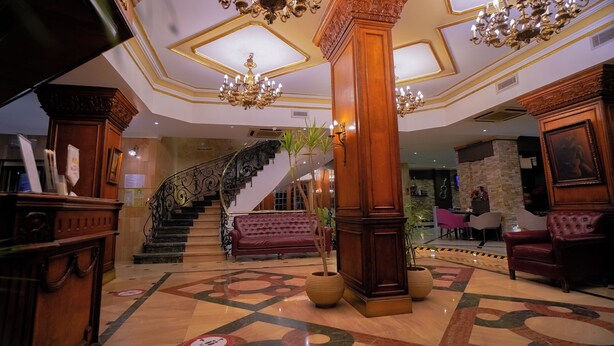 Un vaste hall d’entrée avec un sol en marbre, des lustres somptueux, un escalier et des coins salons confortables.