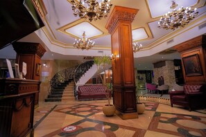 A grand lobby with a marble floor, ornate chandeliers, a staircase, and plush seating areas. - Royal Marshal Hotel (Cairo)