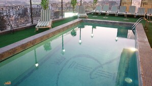 Une piscine sur le toit, dotée de chaises longues et offrant une vue sur le paysage urbain.