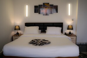 A neatly made bed with white bedding, a black headboard, and two bedside lamps. - Royal Marshal Hotel (Cairo)