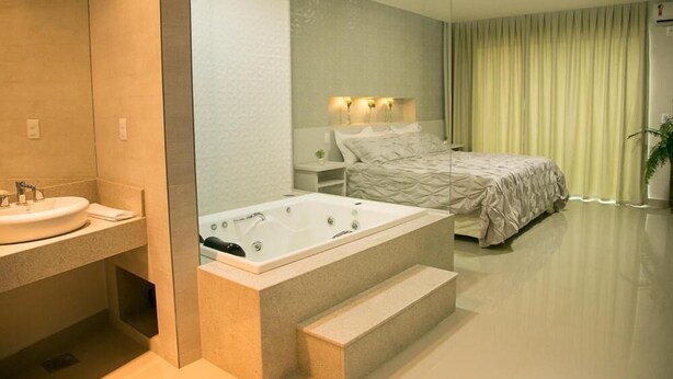 Un dormitorio moderno con una cama grande, un baño independiente con bañera y un espejo amplio.