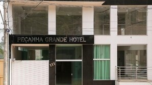 Un hotel llamado "PEÇANHA GRANDE HOTEL" con una fachada moderna, grandes ventanales y una entrada visible.