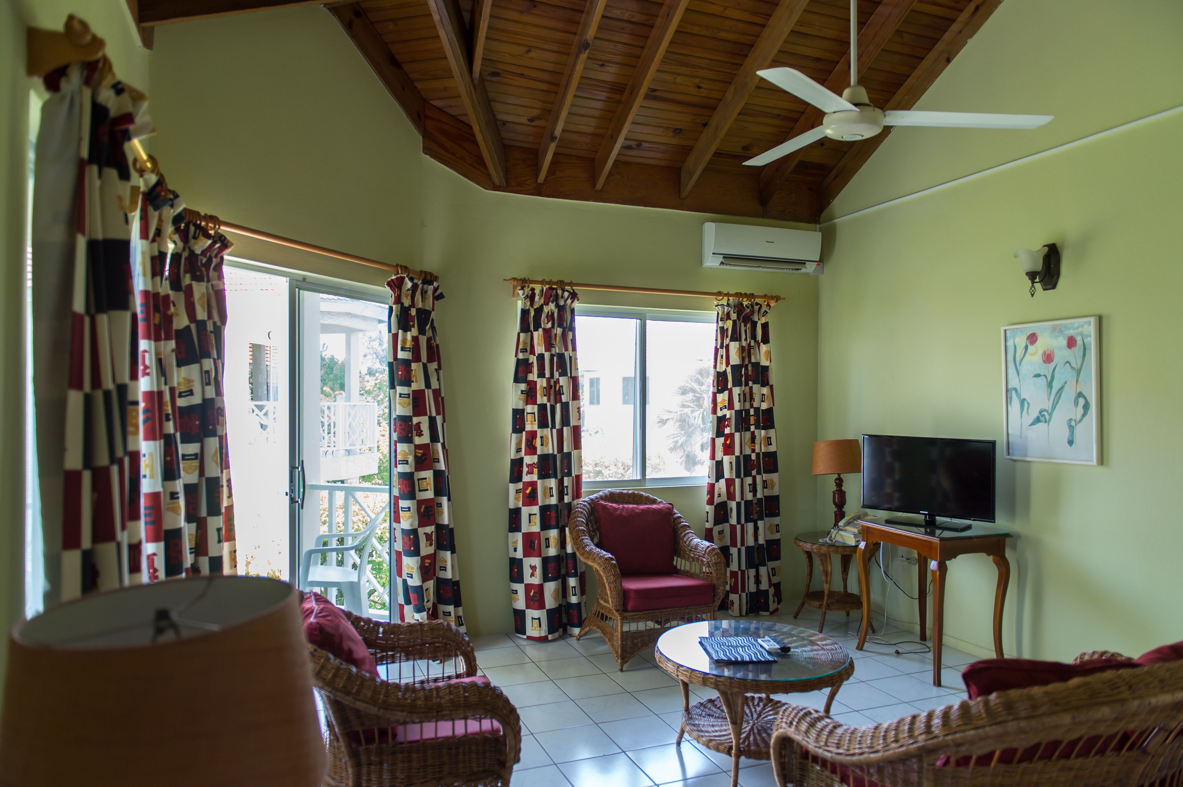 A living room with wicker furniture, a ceiling fan, and a television.