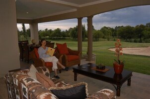 Uma área de estar coberta ao ar livre com vista para um campo de golfe.