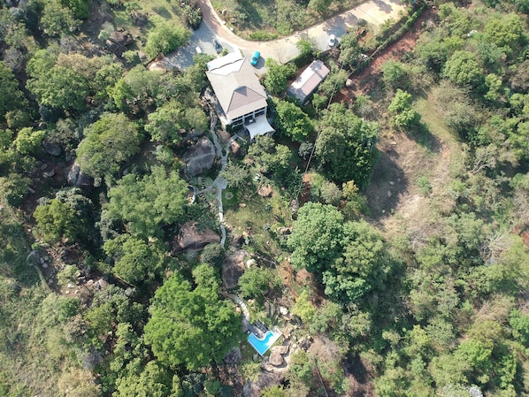 Eine Luftaufnahme eines Anwesens mit Hauptgebäude, Nebengebäude und einem von üppiger Vegetation umgebenen Swimmingpool.