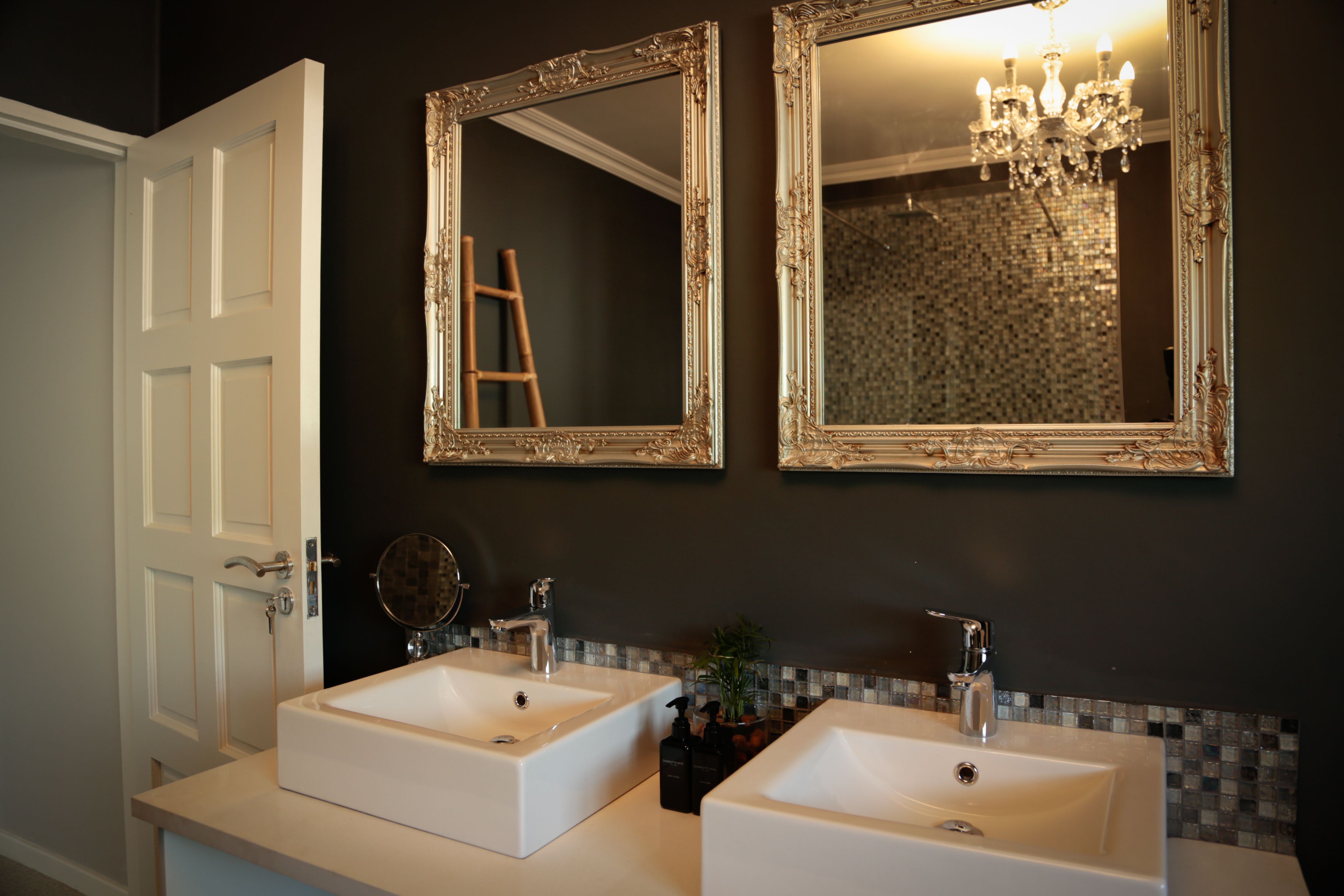 A bathroom with two white sinks, a mirror, and a chandelier.