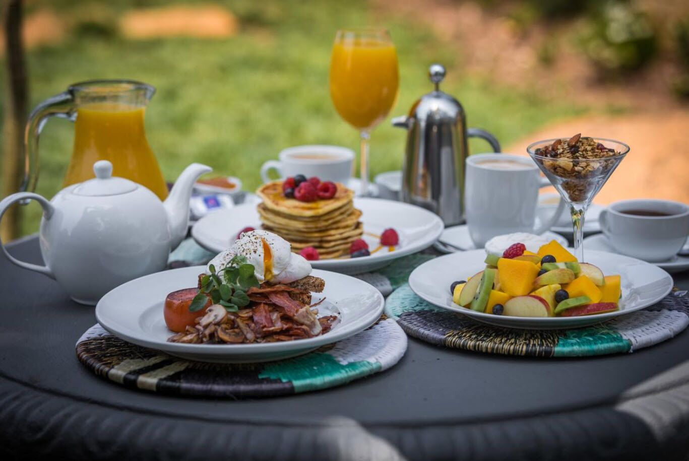 Une table de petit-déjeuner avec divers plats, notamment des crêpes, des œufs et des fruits.