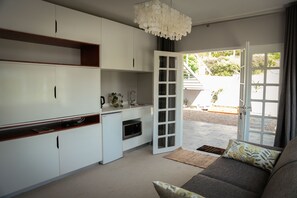 Eine moderne Küche mit weißen Schränken, einem Einbauofen und einer Essecke mit einer Couch und Kissen.
