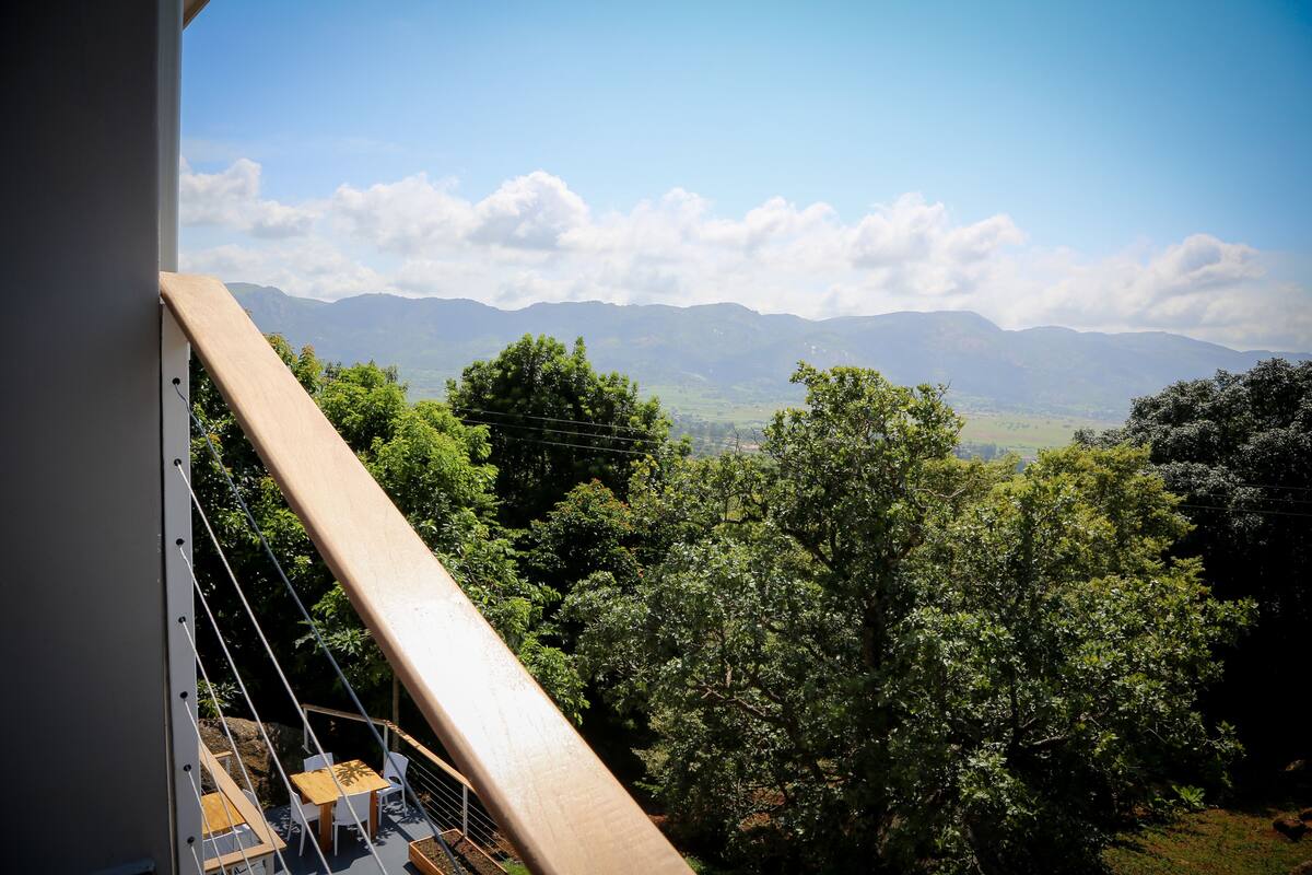 Un balcon avec vue sur les montagnes et les arbres.