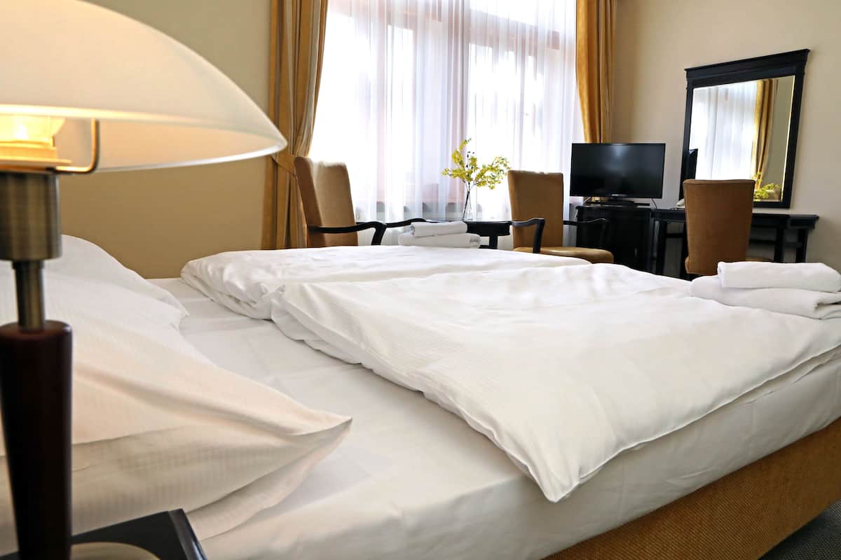 Een hotelkamer met een groot bed, een bureau, een stoel, een televisie en een spiegel.