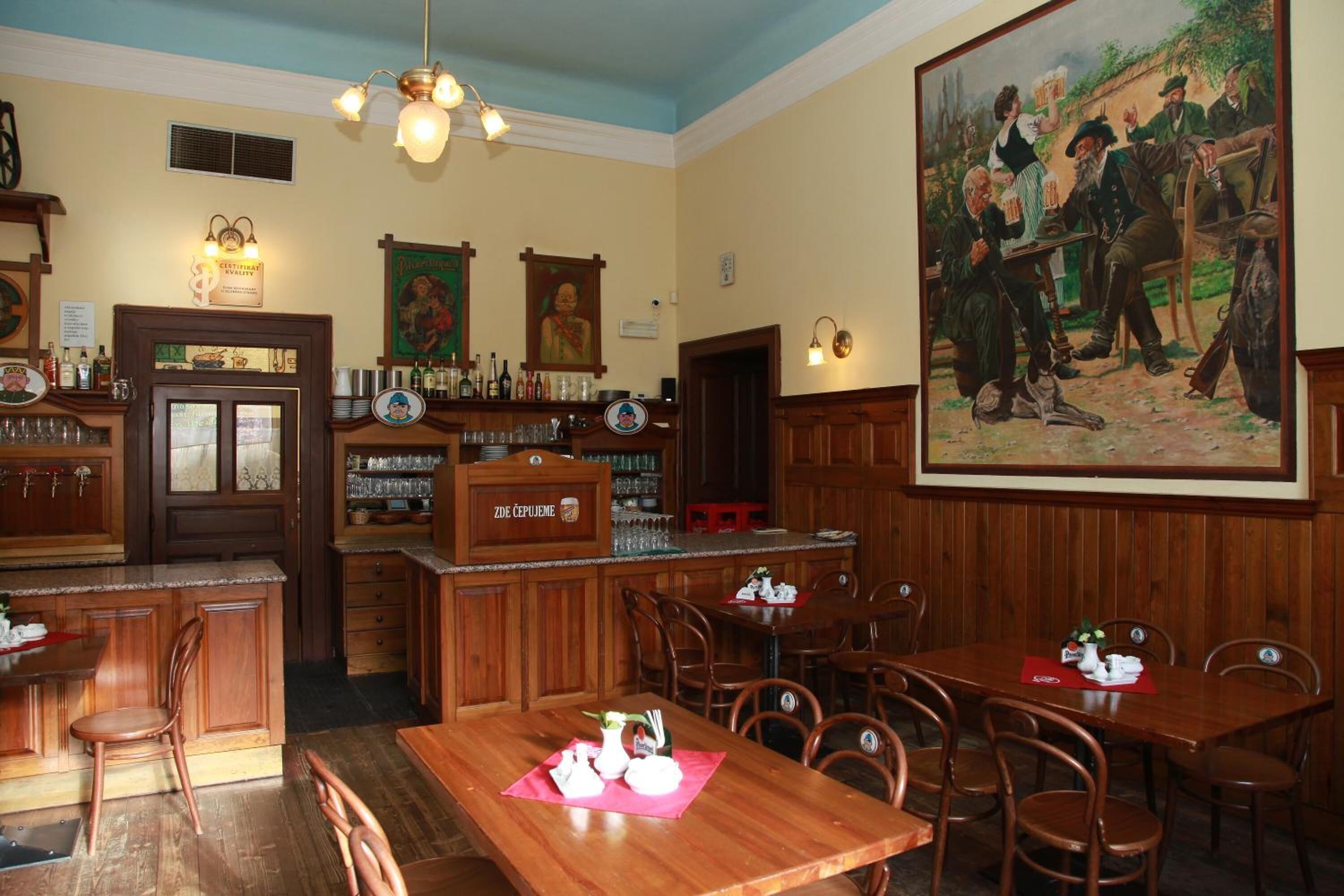 A traditional pub with wooden interiors, a bar area, and a large painting on the wall.