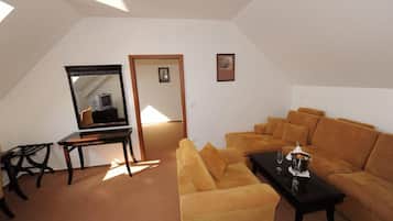 Un salón espacioso con techo alto, un espejo grande, un sofá, una mesa de centro y un escritorio.