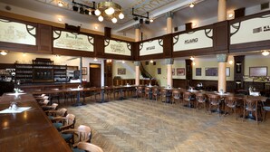 Un restaurant spacieux doté de planchers en bois et de hauts plafonds, avec de nombreuses tables et chaises.