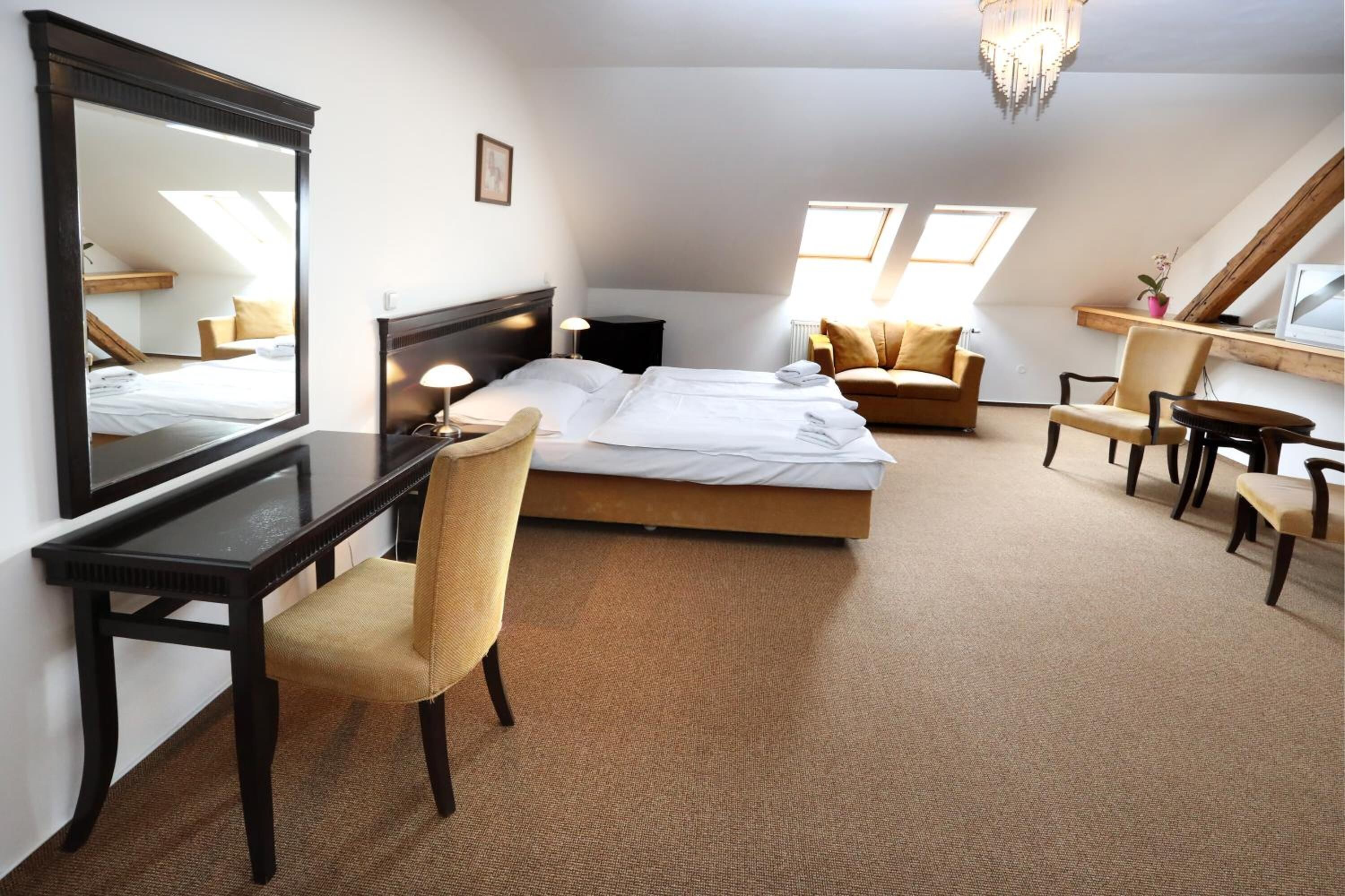 A bedroom with a bed, a desk, a chair, a sofa, and a TV.