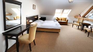A bedroom with a bed, a desk, a chair, a sofa, and a TV.