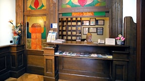 Un comptoir d’accueil avec un revêtement en bois, une vitrine en verre contenant des livres et un mur orné de cadres contenant des certificats.