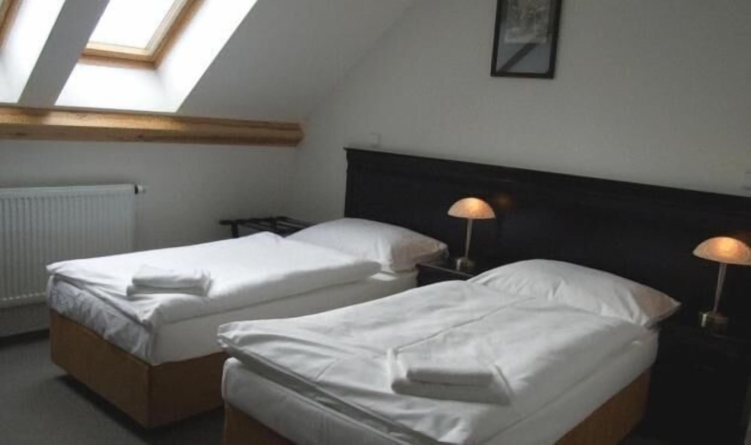 Ein Zimmer mit zwei Einzelbetten, einem Oberlicht, einer Heizung und einem gerahmten Bild an der Wand.