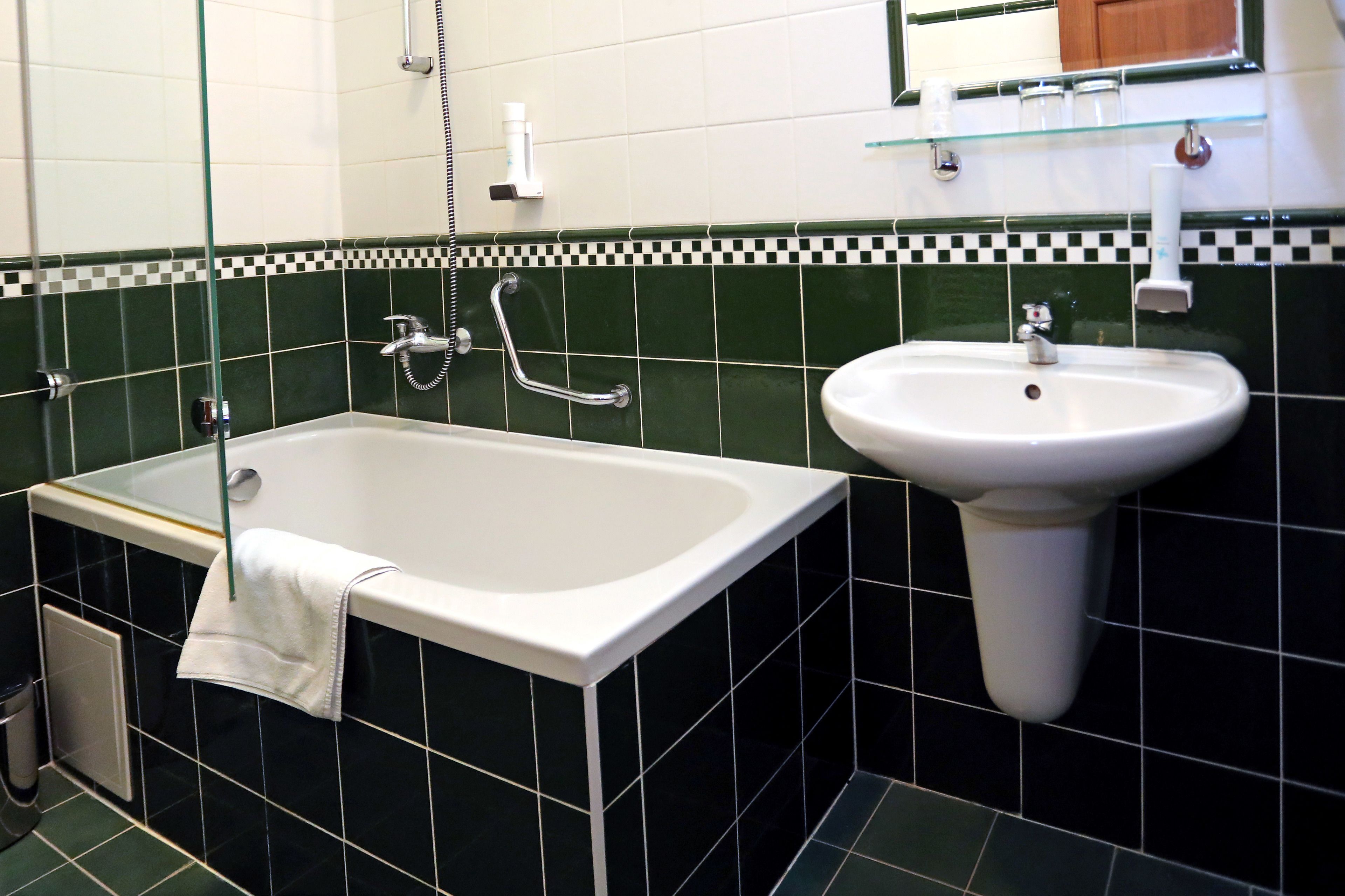 A bathroom with a bathtub, a sink, and a glass shelf above the sink.