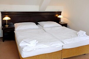 Una cama doble con sábanas blancas y dos lámparas de noche.