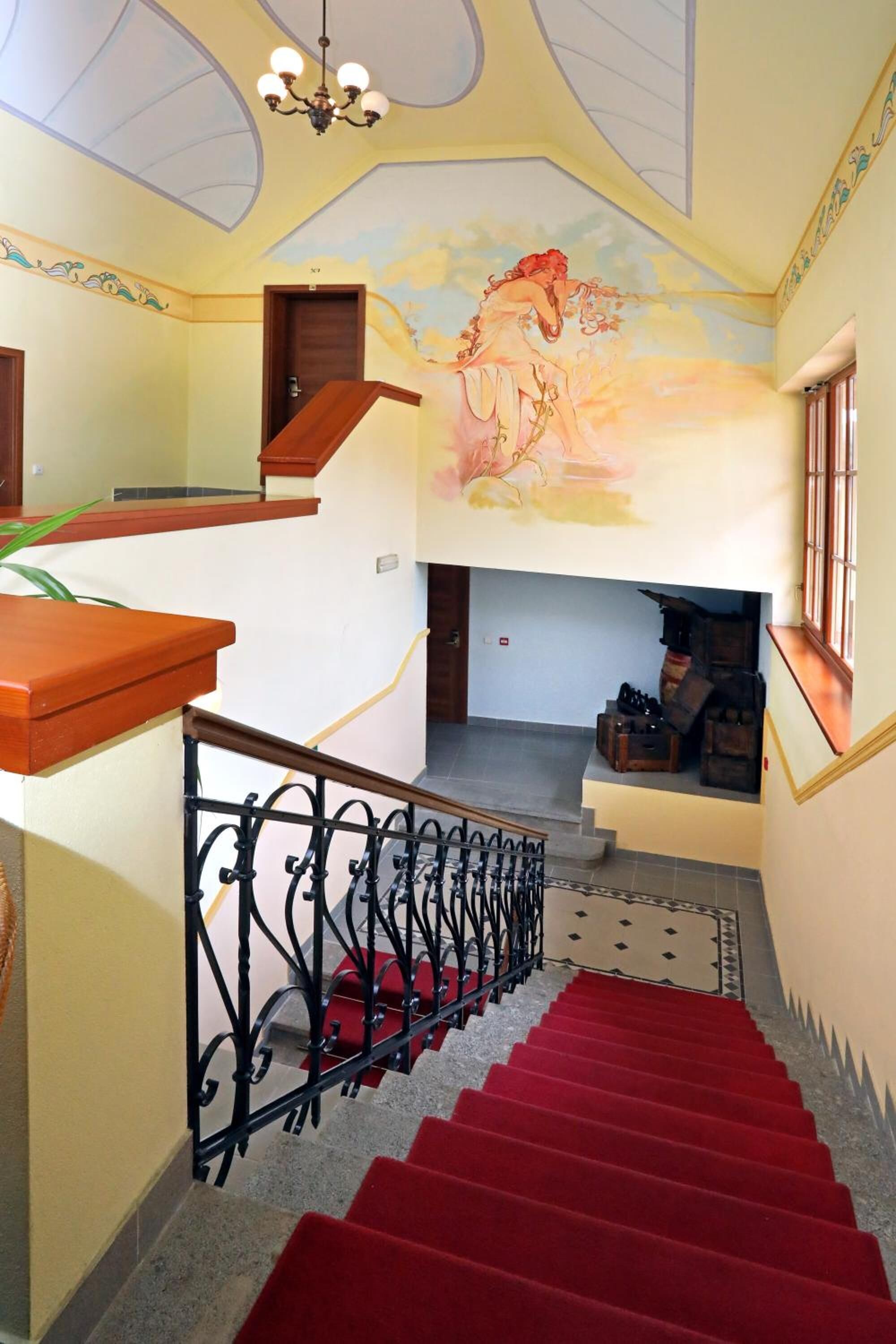 A staircase with red carpet, a decorative railing, and a mural on the wall.