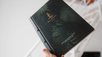 Une main tenant un livre noir intitulé « The Hotel Lobby », avec des lettres dorées sur la couverture.