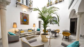 Relax in a stylish lounge area with sofas, armchairs, and a coffee table, surrounded by artwork and a large potted plant.