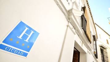 A sign with a blue background and white letters spelling "H CIUDAD" on a white wall.