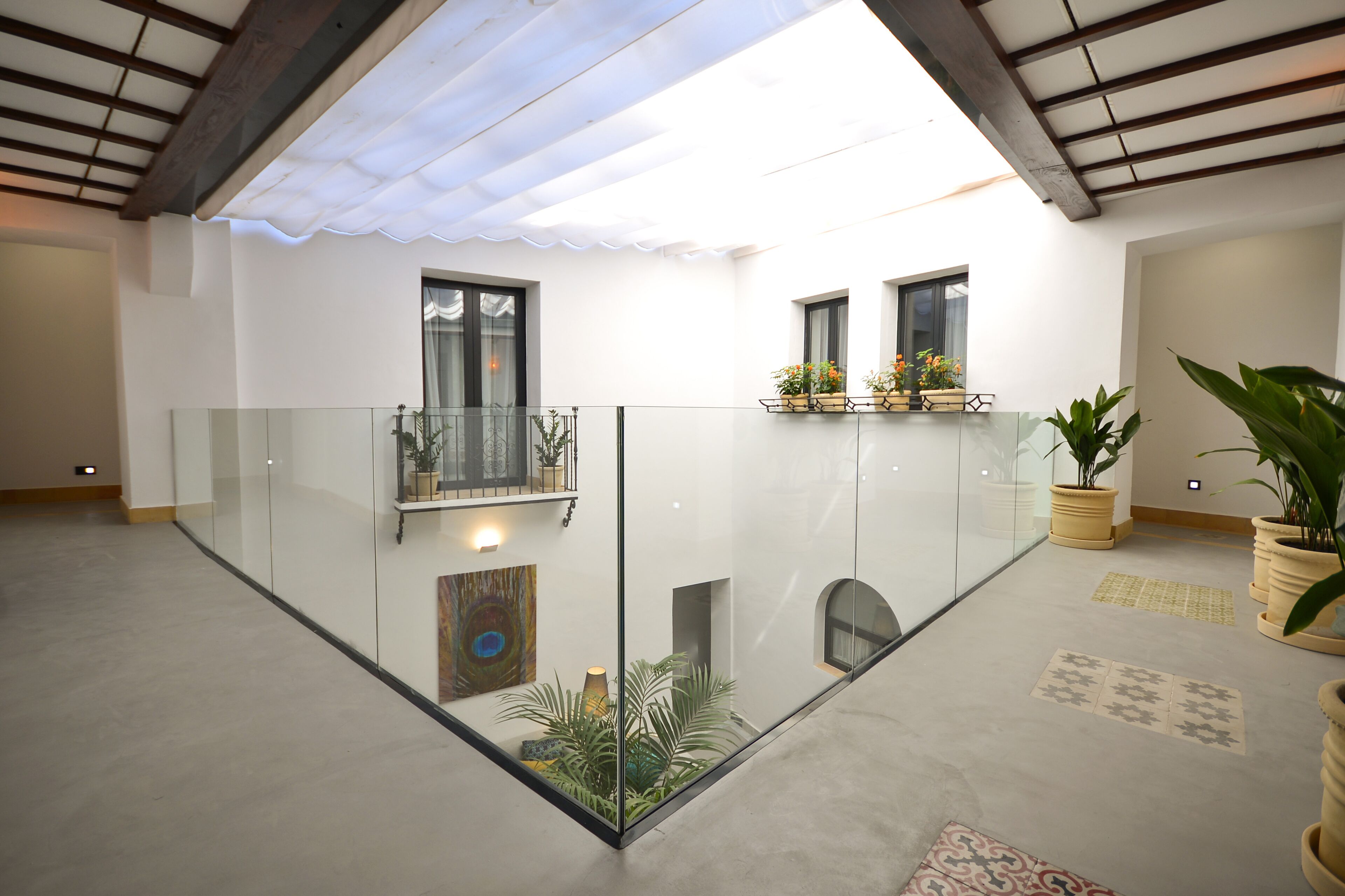 A spacious indoor area with a glass railing, potted plants, and artwork on the walls.