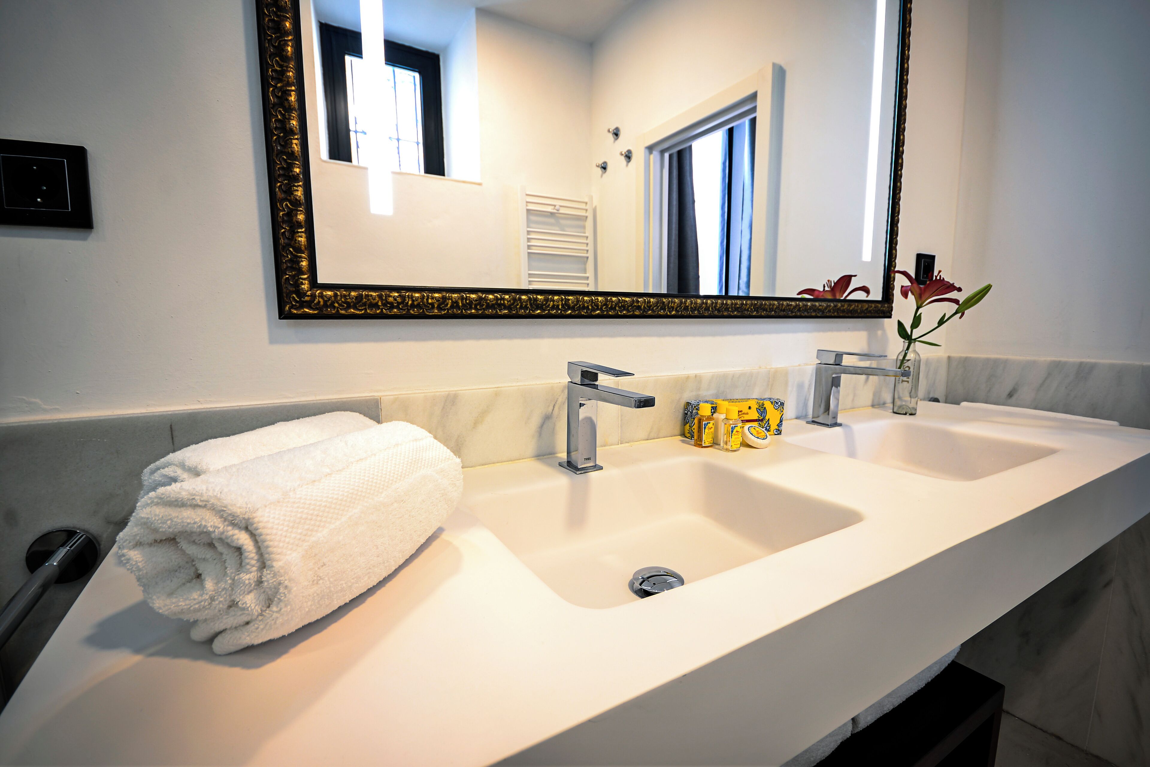 A bathroom with a double sink, a large mirror, and a towel on the side.