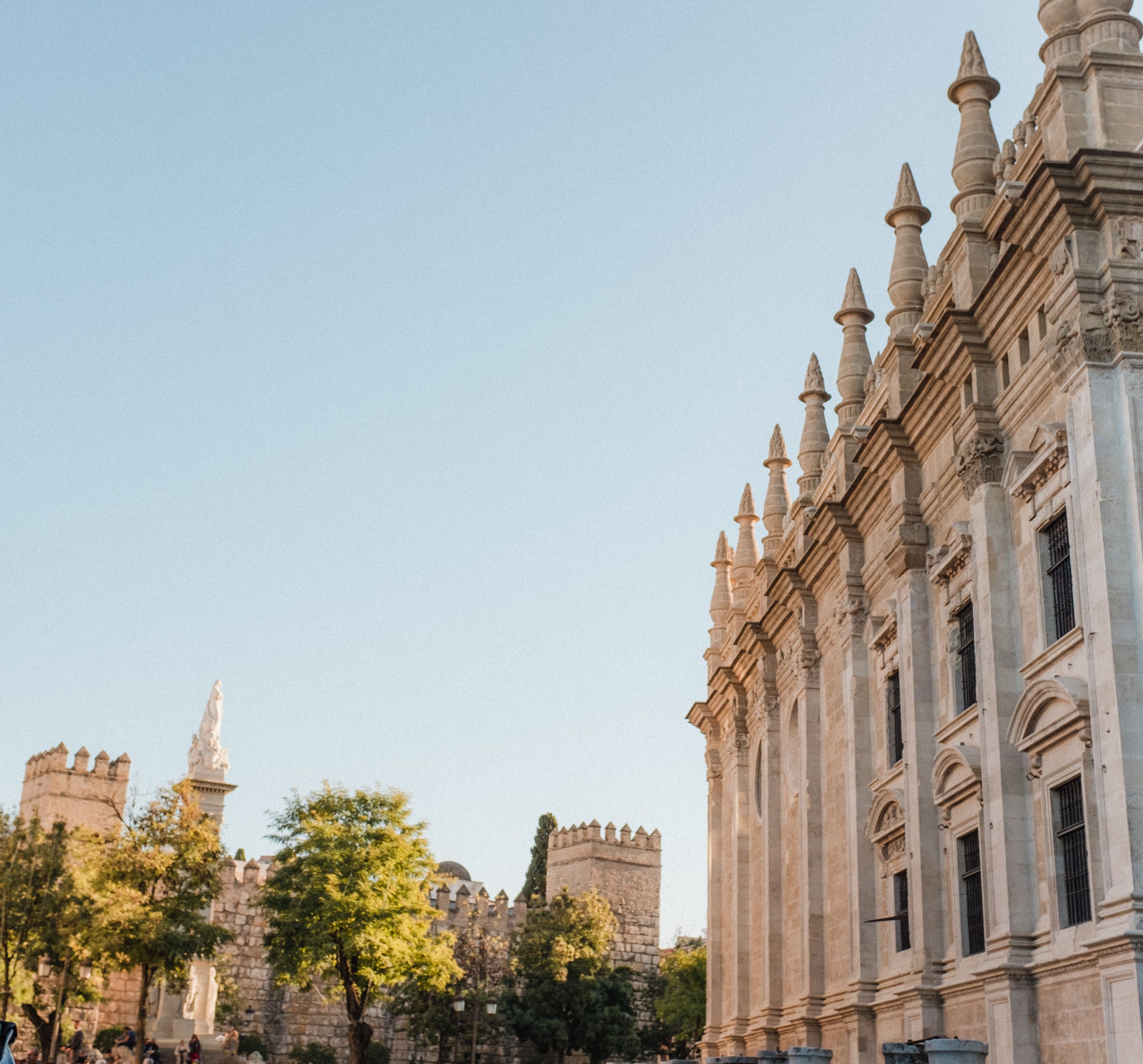 A historic building with ornate columns and a castle in the background.