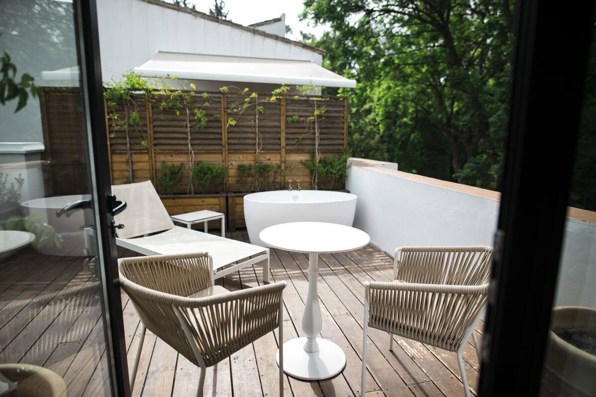 An outdoor patio with wicker furniture, a round table, and a white umbrella.
